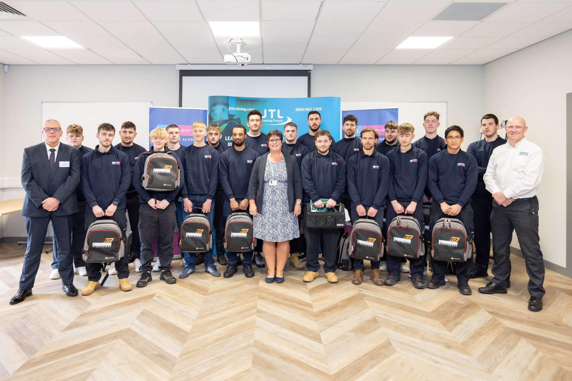 apprentices pose for group photo holding their toolkits